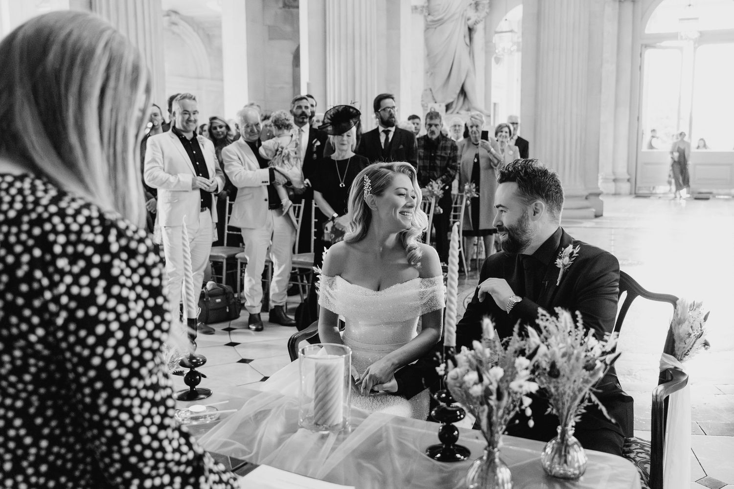 Wedding reception guests seated at elegant tables with black candelabras in grand white columned hall.  city hall dublin wedding photos