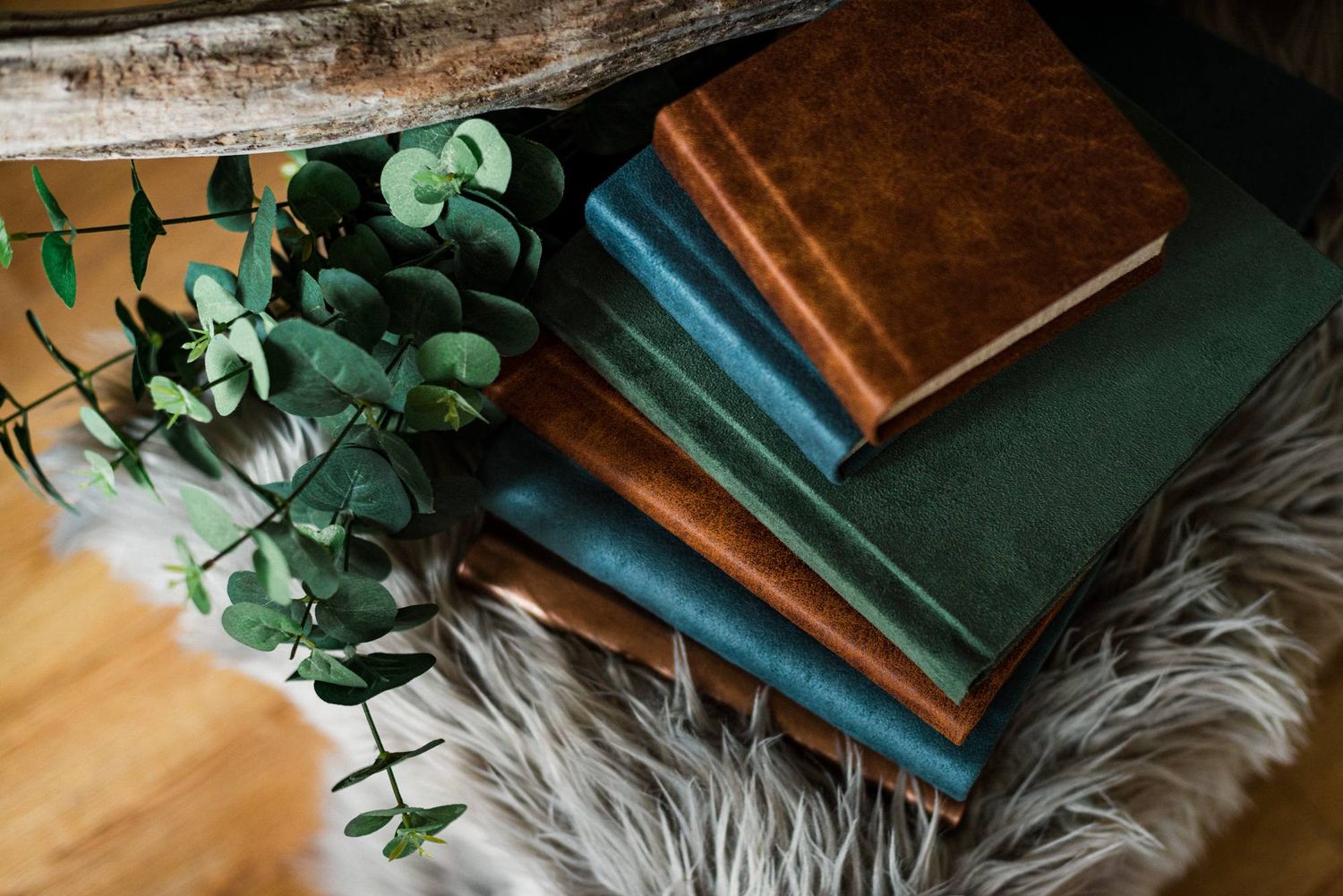 Stack of vintage books with green and brown covers on a furry blanket with eucalyptus leaves. Wedding photographer Dublin