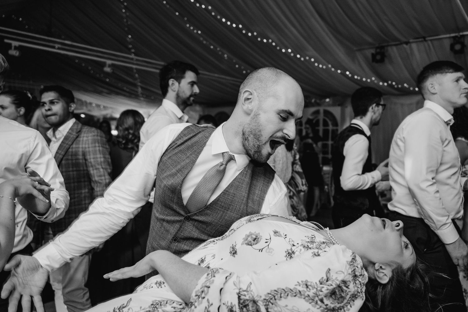 Black and white photo of wedding guests dancing energetically at a reception. LGBTQ Ashley Park Wedding Photographer