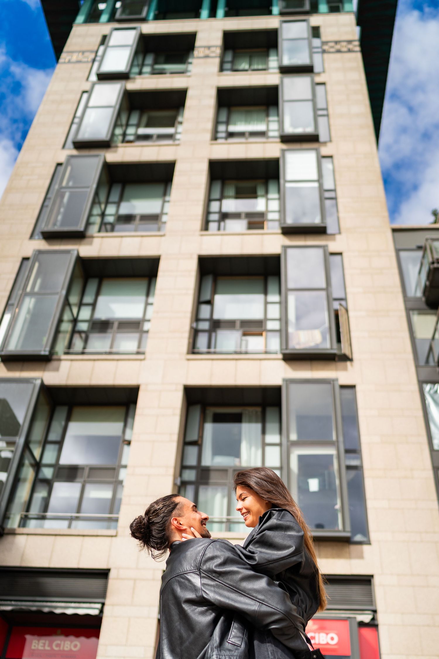 Modern apartment building exterior with glass balconies against a blue sky. Couple's Photoshoot PHOTOGRAPHER Dublin
