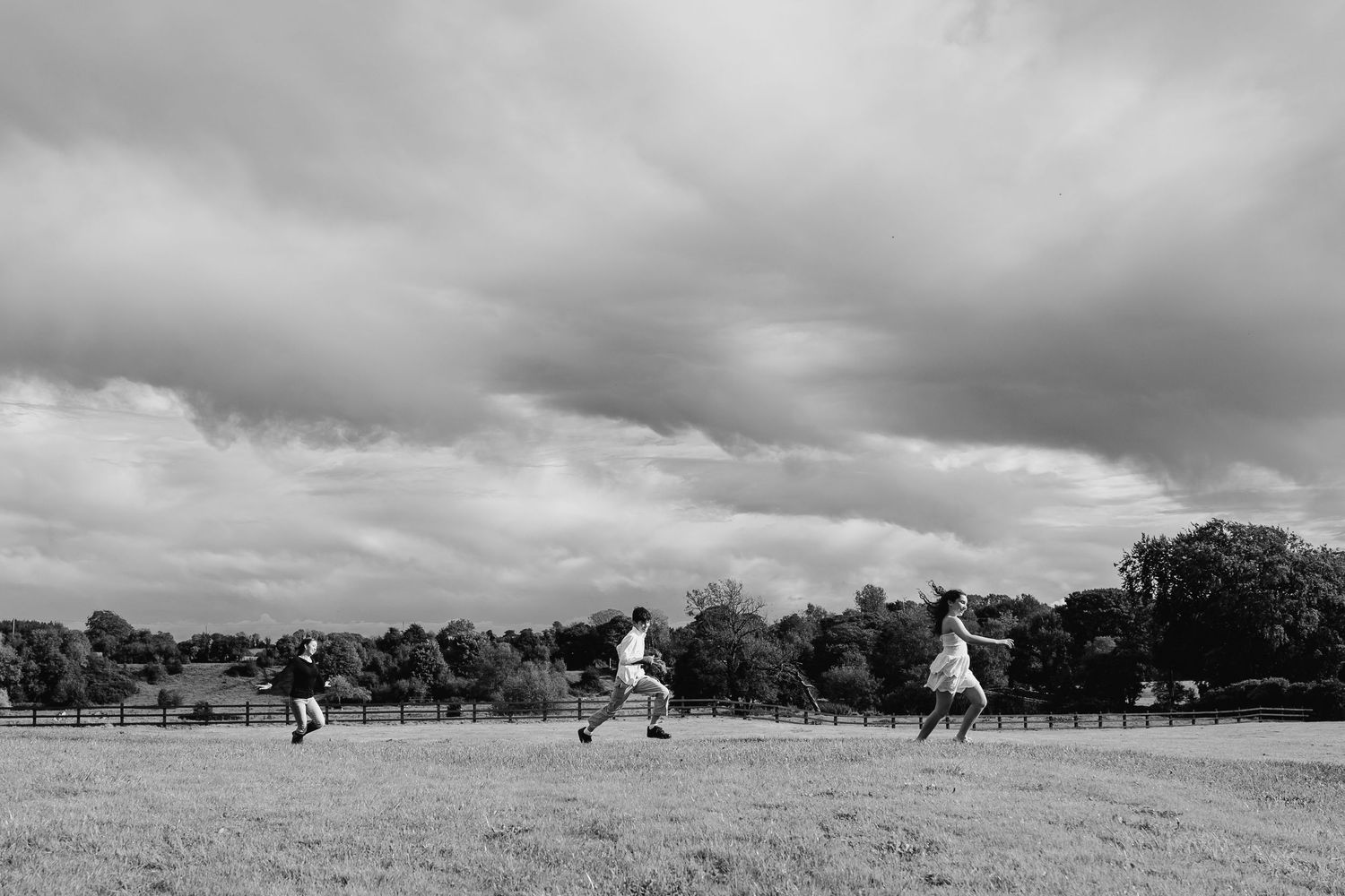 Black and white panoramic landscape with figures running in distant field. BEctive abbey family photographer dublin