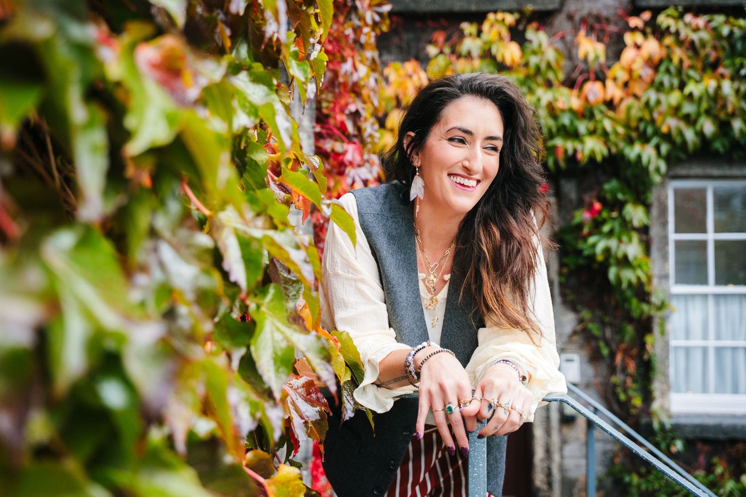 Two people laugh and embrace in front of autumn foliage and stone buildings. professional headshots dublin photographer