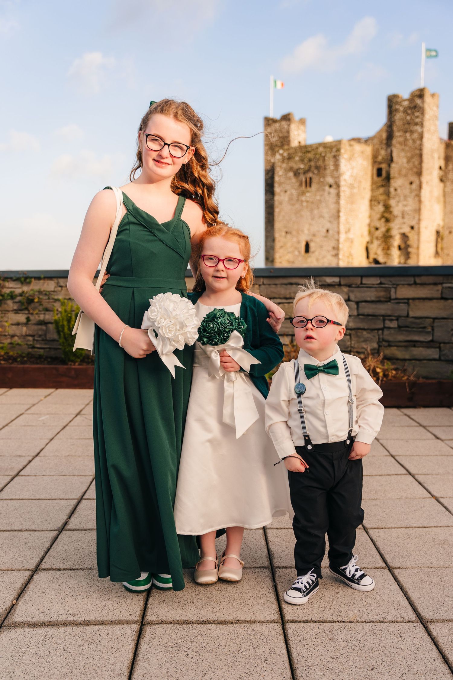 Wedding party members pose in emerald green and formal attire near a historic castle.  Wedding PHOTOGRAPHER Trim Castle