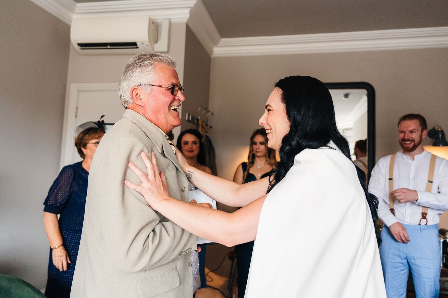 Group sharing candid laughs and embraces in a bright indoor setting. House Dublin Wedding Photographer