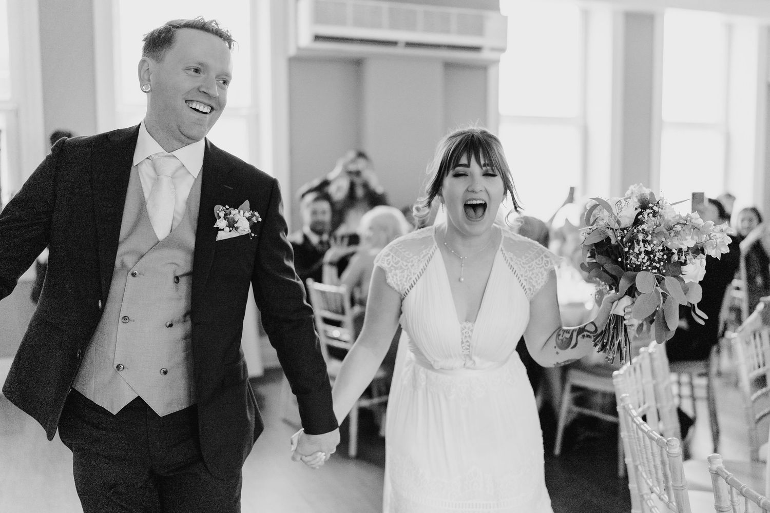 Joyful couple walks hand in hand through reception venue in black and white photography. PHOTOGRAPHER Dublin Ireland Wedding