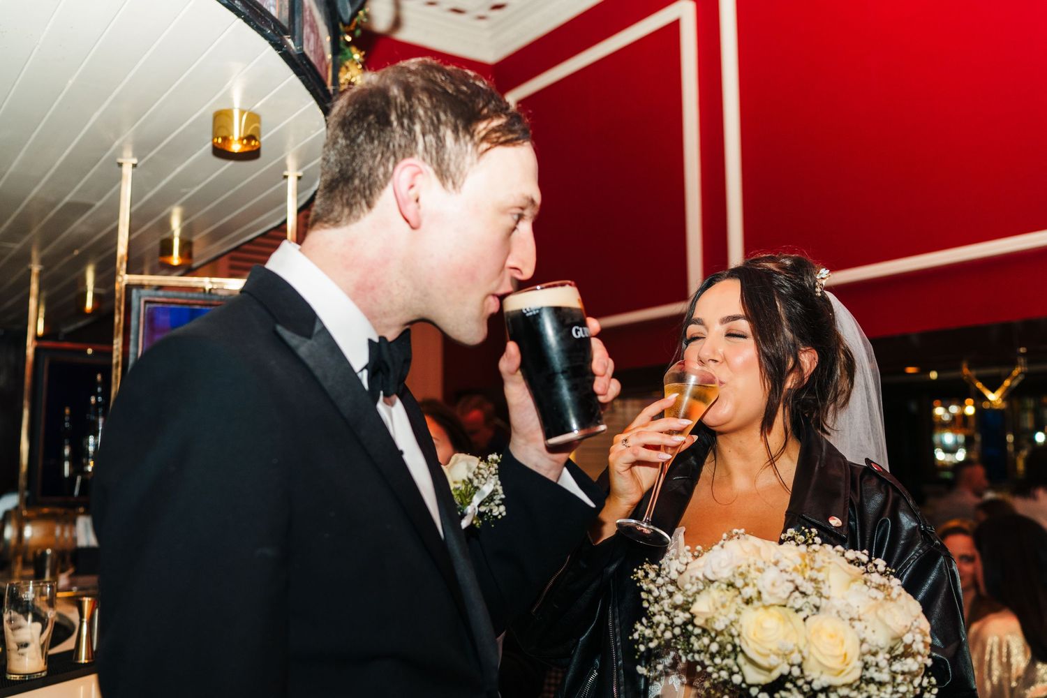 Celebratory moment at bar with couple sharing drinks during wedding reception. Wedding PHOTOGRAPHER Dublin