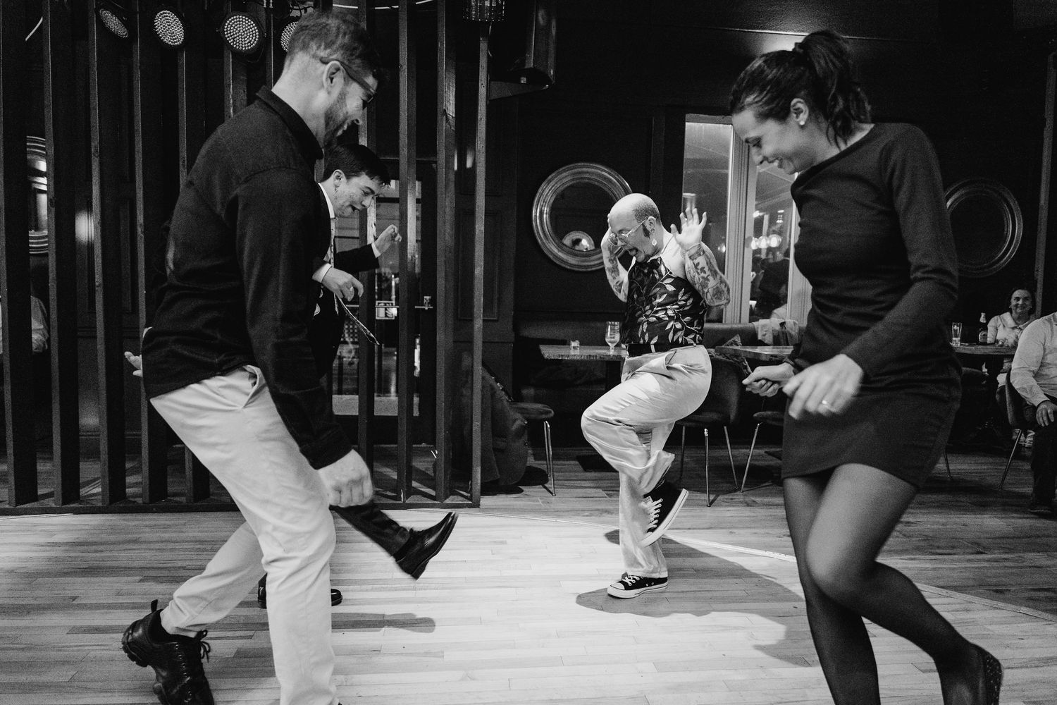 Poulaphouca Wedding photographer wicklow  Three dancers perform energetic moves on a dance floor in black and white photography.