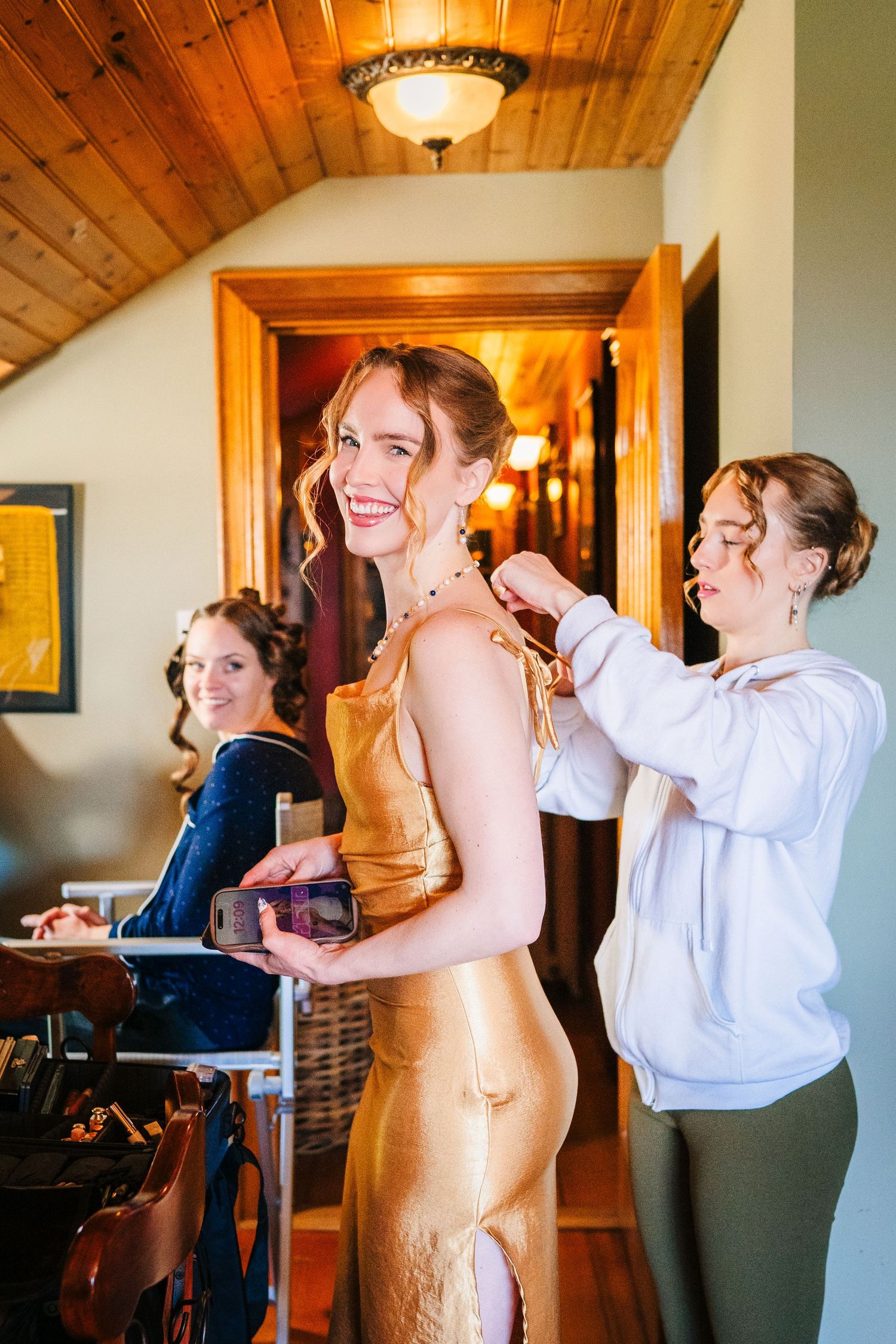 People help with preparations in a wood-paneled room with warm lighting during a special occasion.Poulaphouca Wedding photographer wicklow