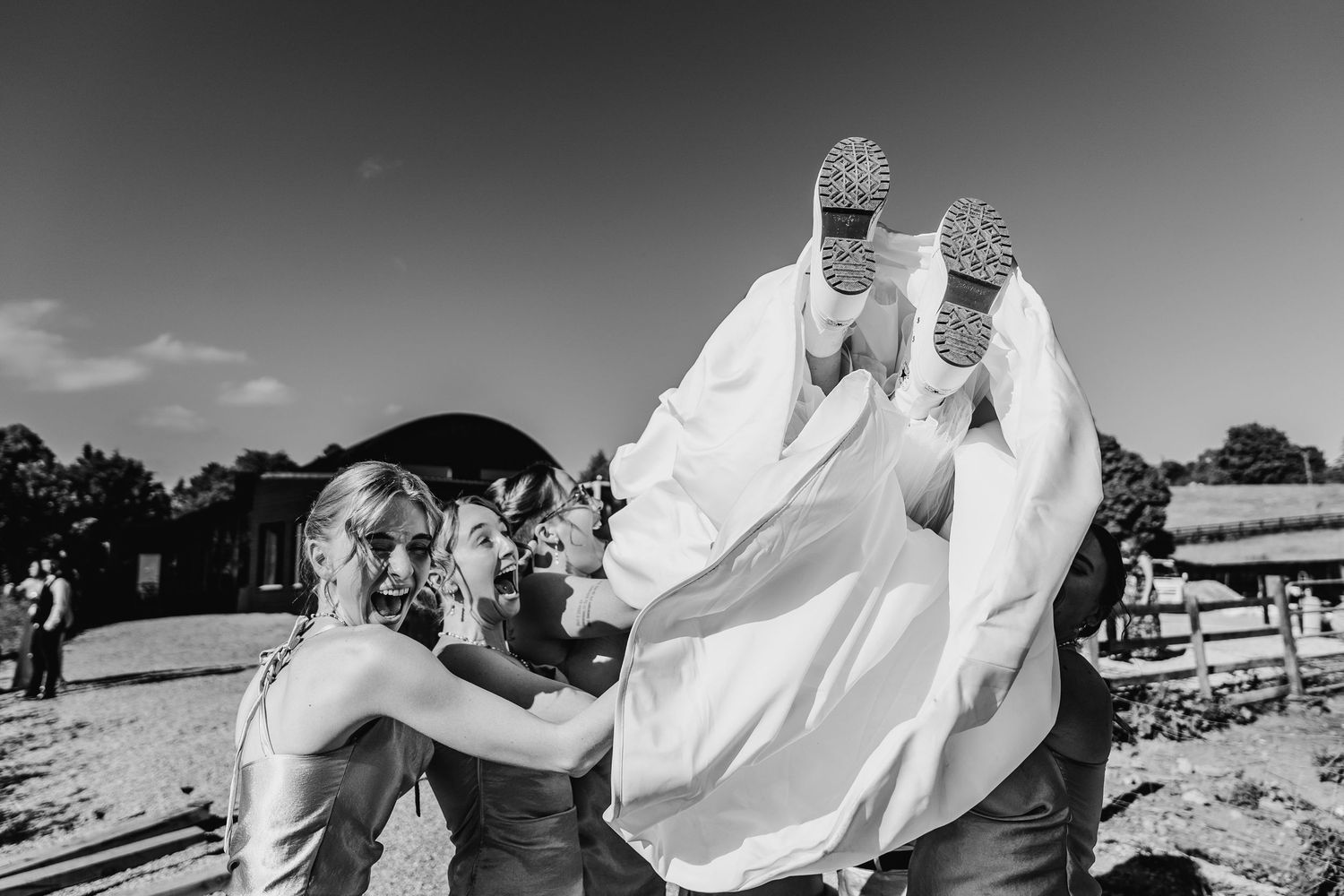 Poulaphouca Wedding photographer wicklow A playful black and white wedding photo showing guests helping lift someone in a flowy dress.