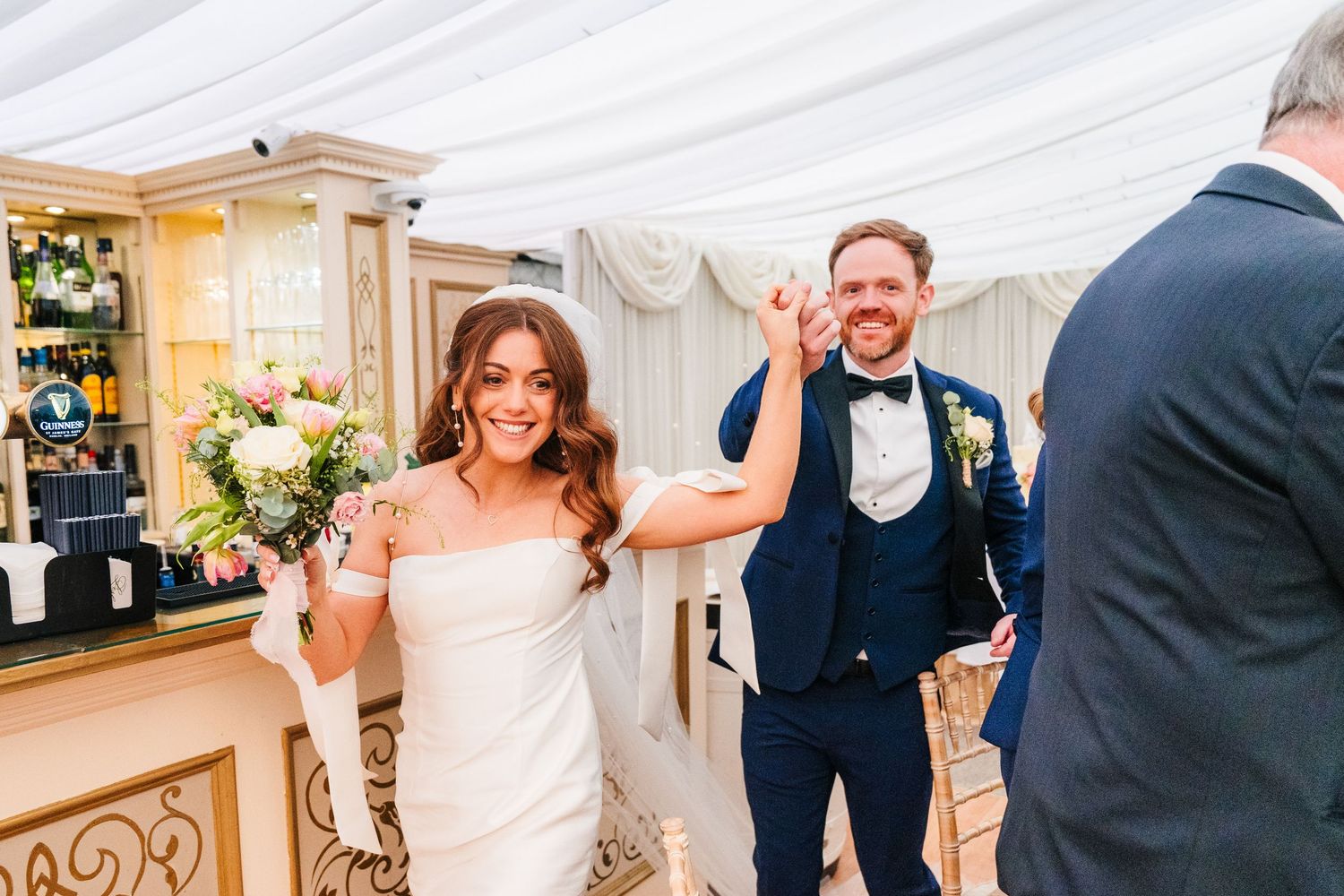 Castle Leslie Wedding Photographer A joyful wedding celebration moment captured in an elegant white reception tent with floral decorations.