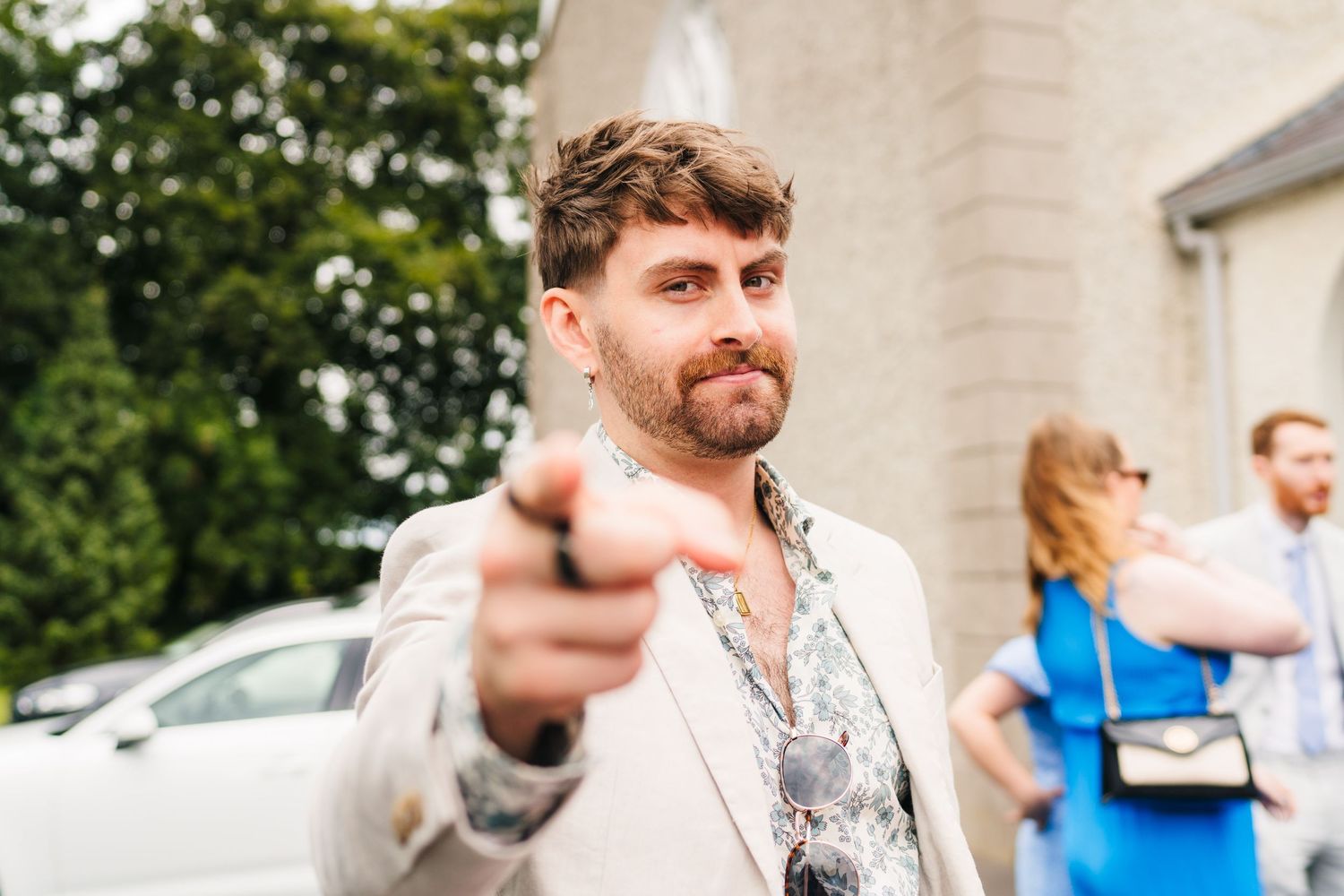Millhouse slane wedding photographer dublin Wedding guests mingle outside a stone church building on a sunny day.