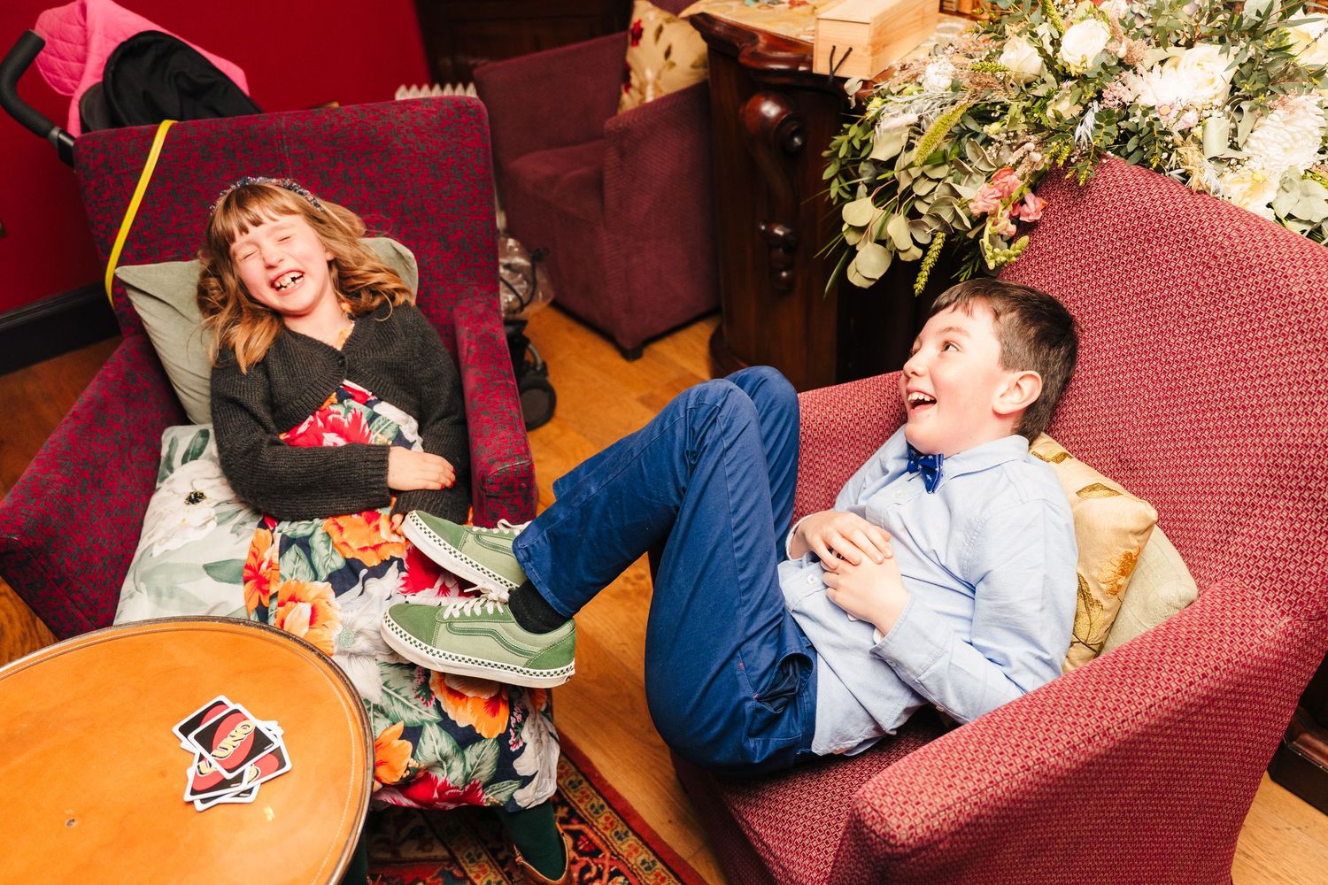 Guests relaxing and sharing laughs on red couches during a wedding celebration. Marco Pierre Dublin Wedding Photographer