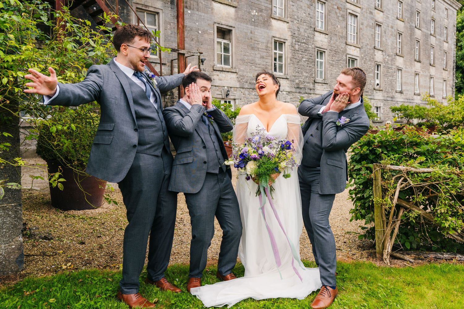 Wedding party celebrates with champagne toasts outside historic stone building on sunny day. Wedding PHOTOGRAPHER Dublin