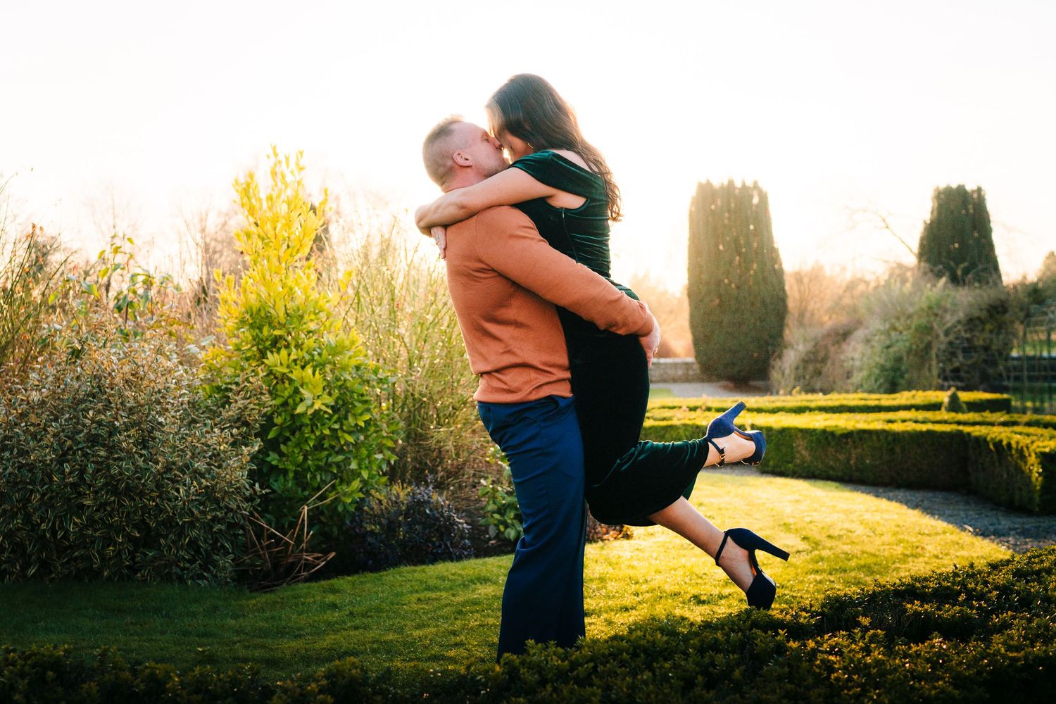 A couple share a romantic embrace in a garden at sunset while one person lifts the other off the ground. PHOTOGRAPHER Dublin ireland