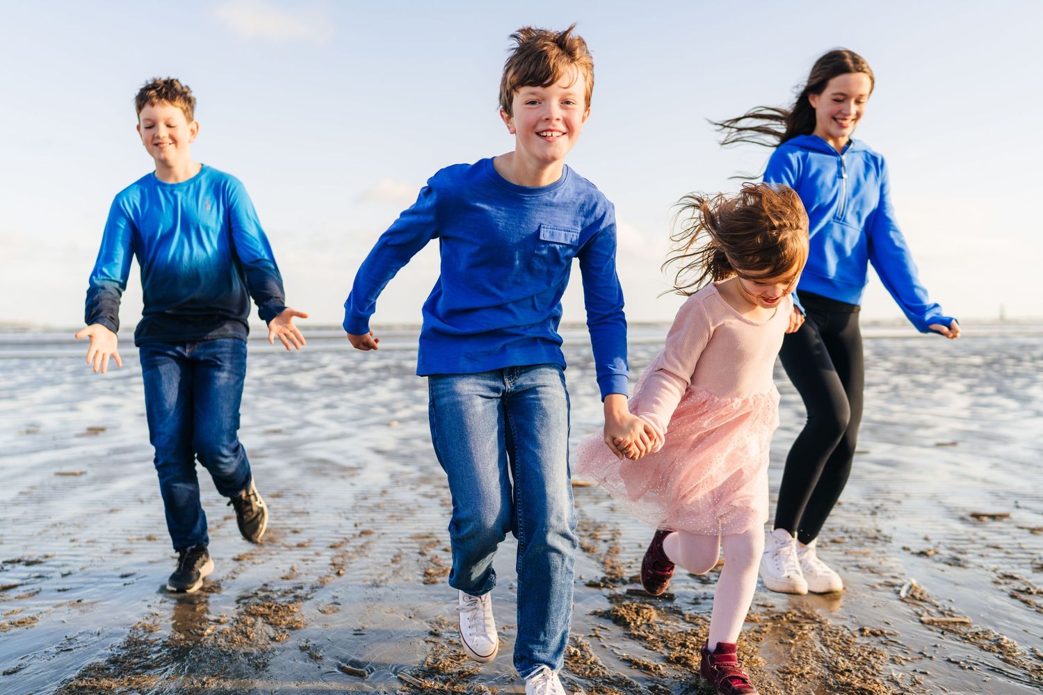 A collection of joyful moments captured on a beach as people splash and play in the shallow ocean water. family PHOTOGRAPHER Dublin