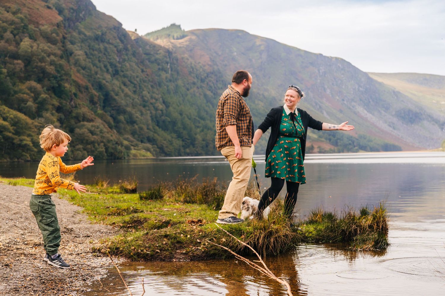 A family enjoys a playful moment together by a serene mountain lake on an autumn afternoon. Family PHOTOGRAPHER Dublin family PHOTOGRAPHER D