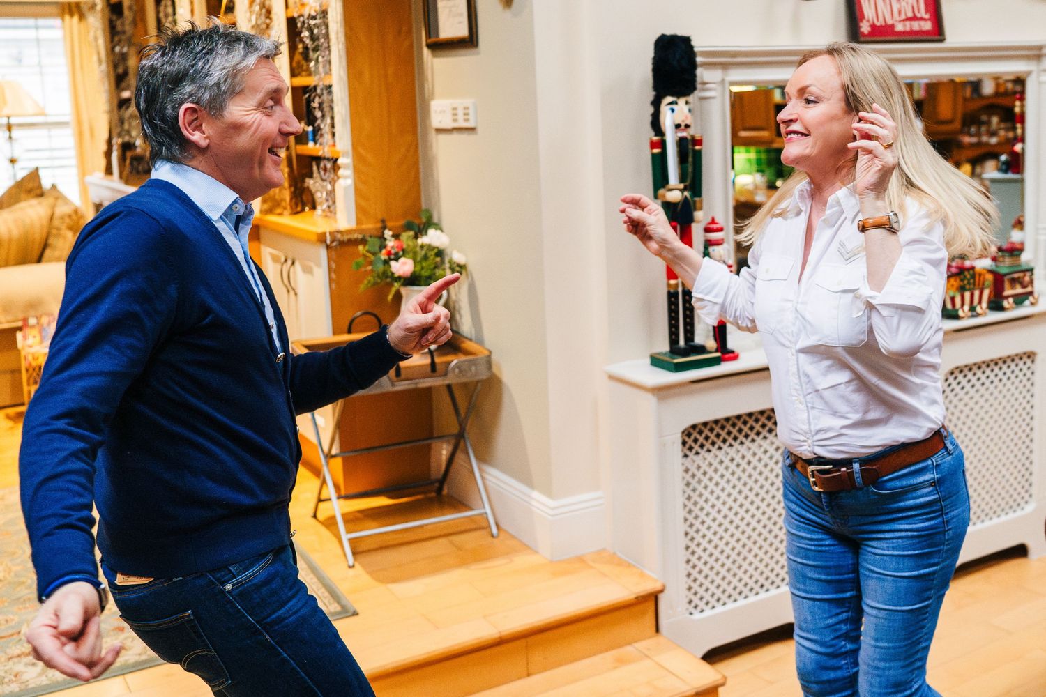 Two people having a lively conversation while standing in a cozy home with wooden stairs and decorative interior. PHOTOGRAPHER Dublin irelan