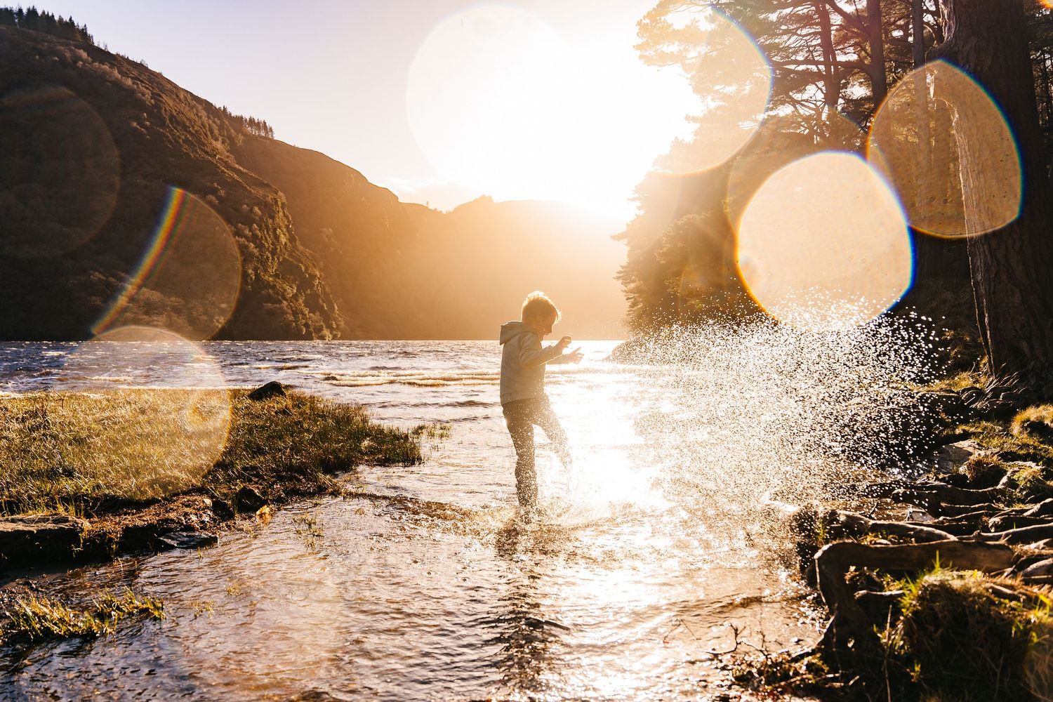 Silhouetted figures playing and splashing in water during golden sunset. Family PHOTOGRAPHER Dublin Family Photographer Dublin