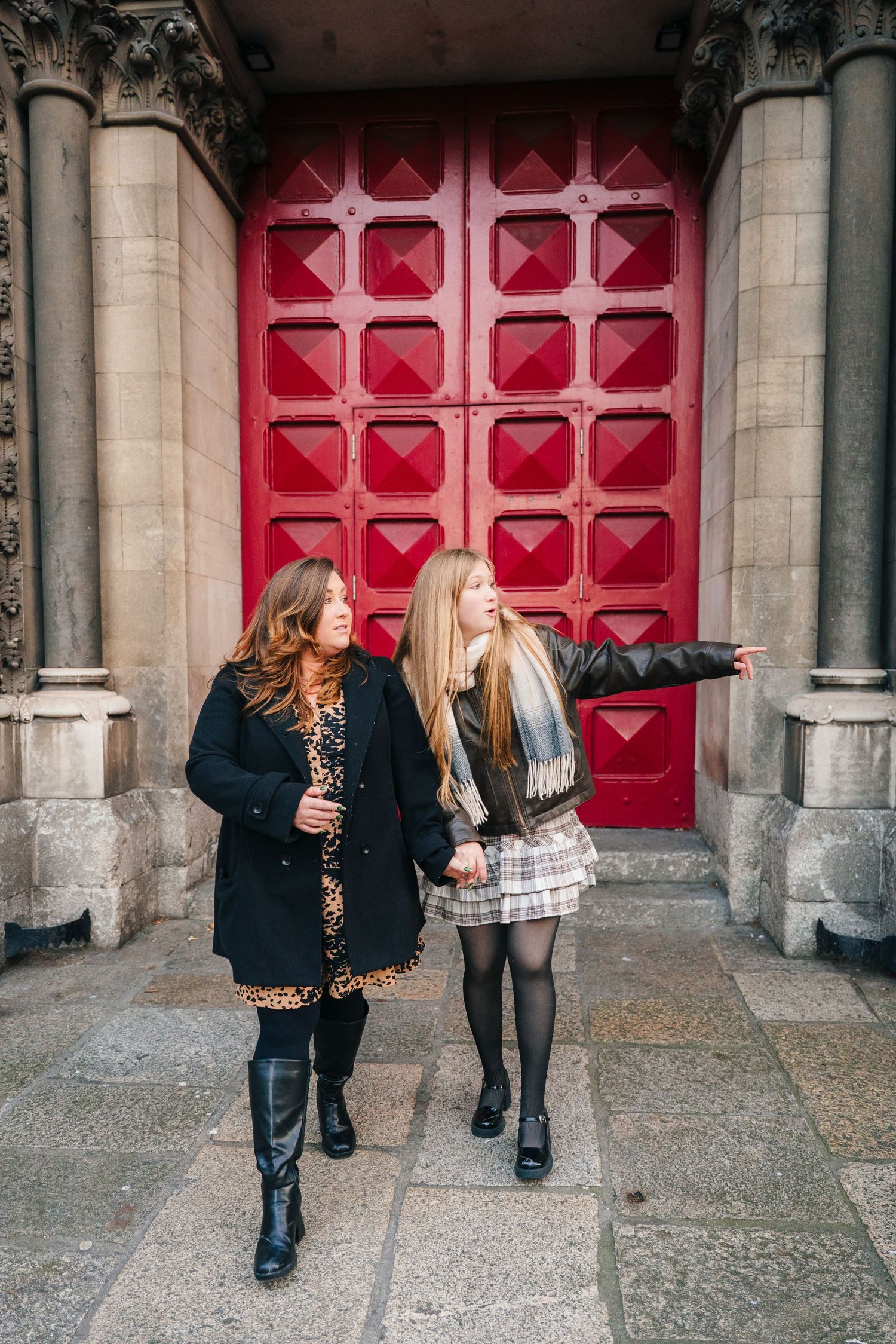 People walking past distinctive red church doors with geometric patterns. family PHOTOGRAPHER Dublin