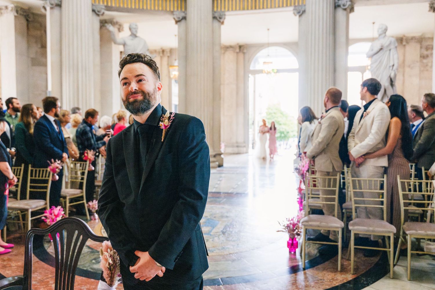 Wedding ceremony venue with white columns and gold accents showing rows of chairs and gathered guests.  city hall dublin wedding photos