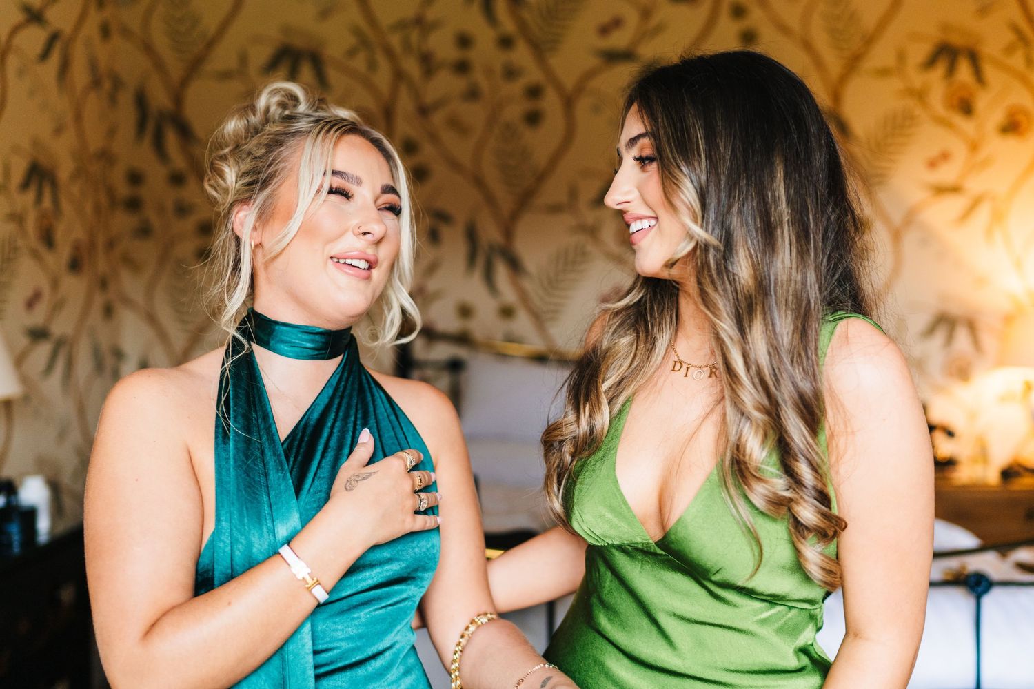 Two people in turquoise and lime green dresses laugh together in a warmly lit room during a celebration.  Virginia Park Lodge Wedding Photog