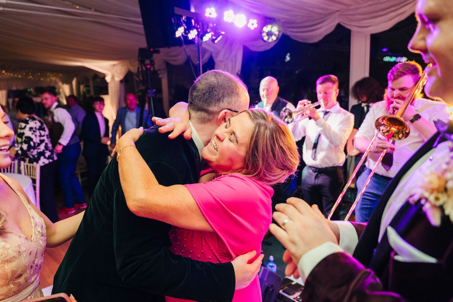 Lively dance party scene with purple and pink lighting at a wedding reception. LGBTQ Ashley Park Wedding Photographer