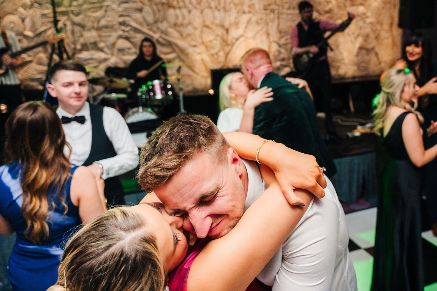 Dancing couples celebrate on the dance floor with a live band performing in the background. Wedding photographer dublin
