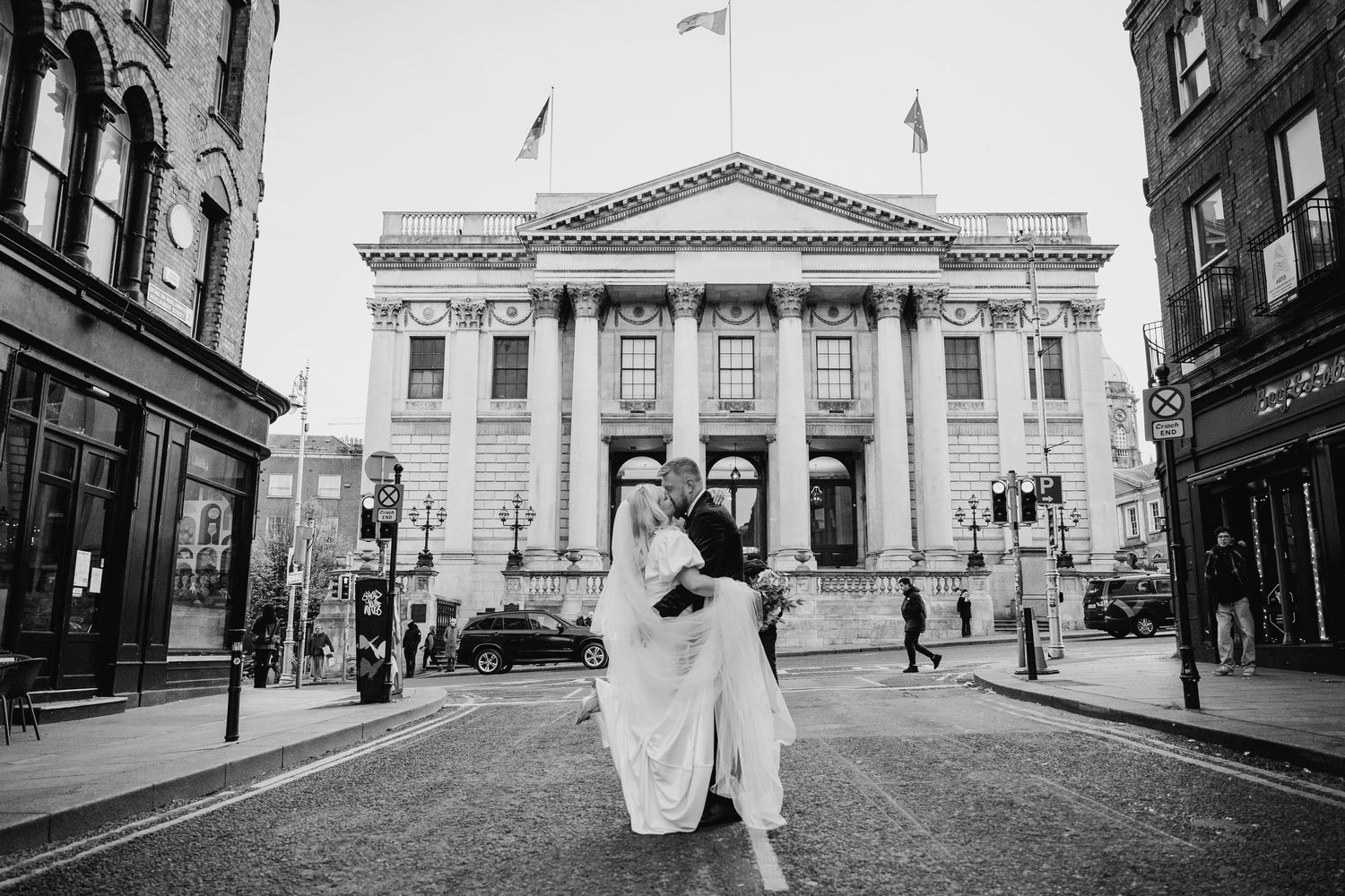 Wide angle black and white shot of couple in front of classical building. Wedding photographer dublin