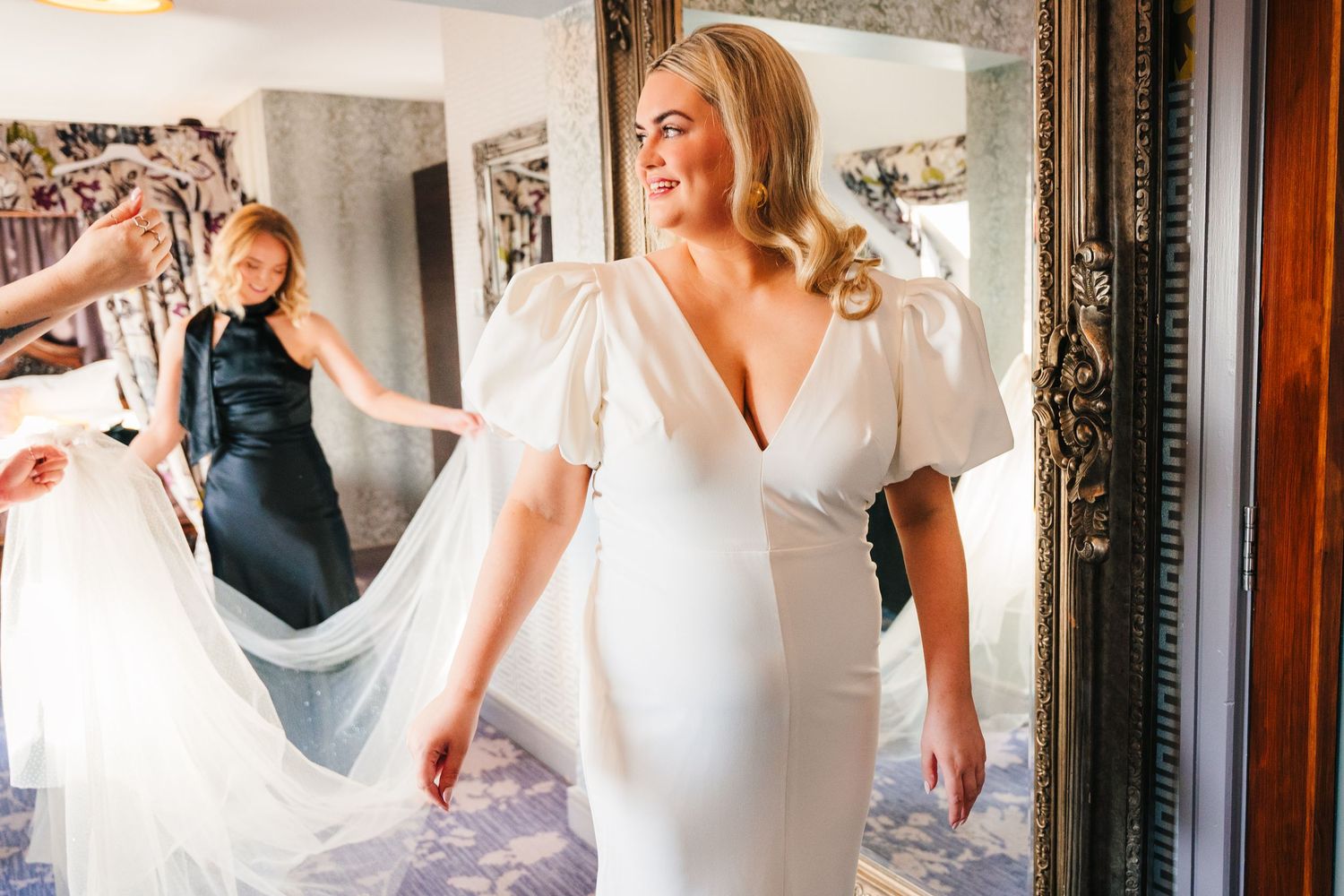A person in a white dress stands in front of a mirror during wedding preparations. Wedding photographer dublin