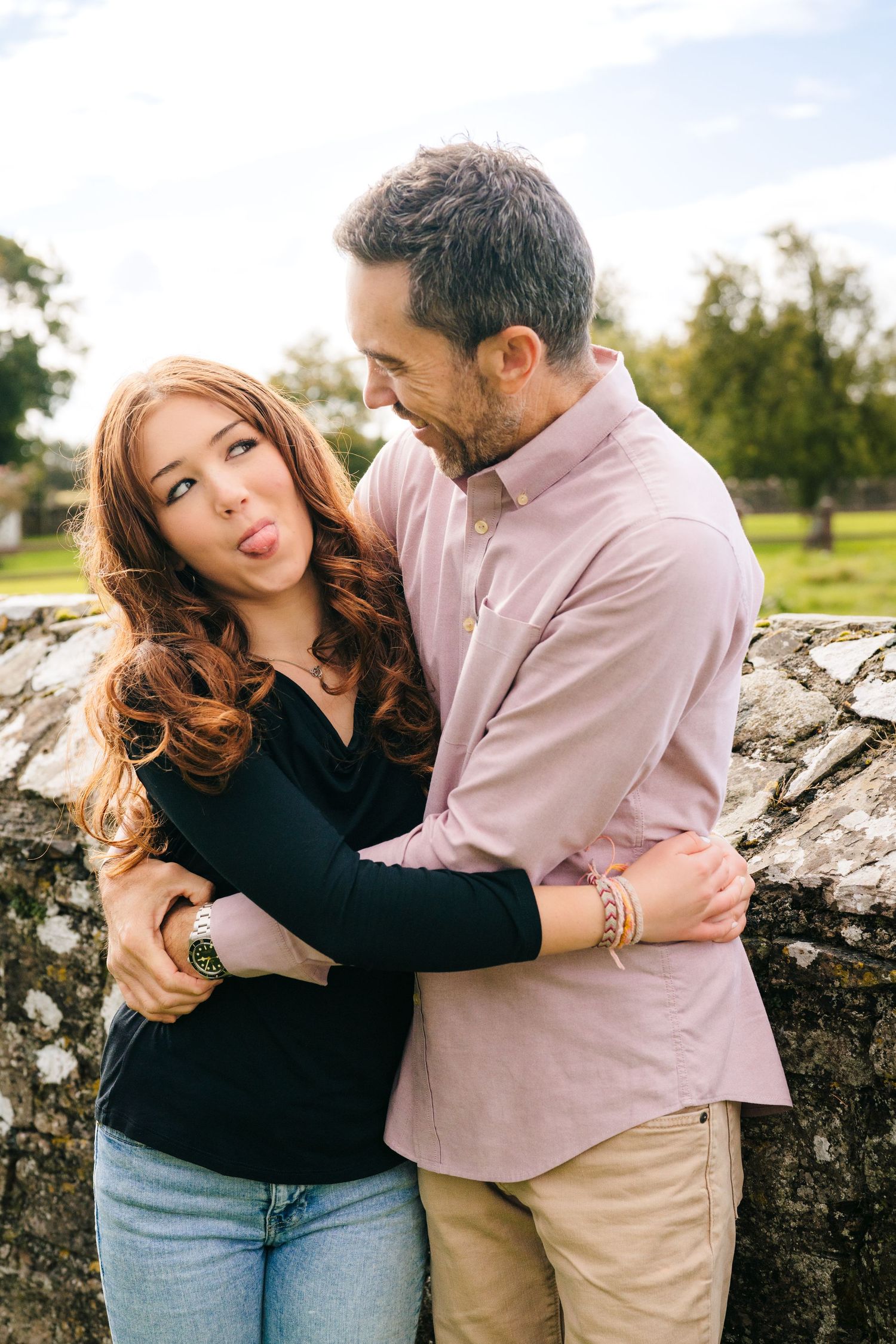 Playful couple poses against ancient stone walls during outdoor photo session. BEctive abbey family photographer dublin