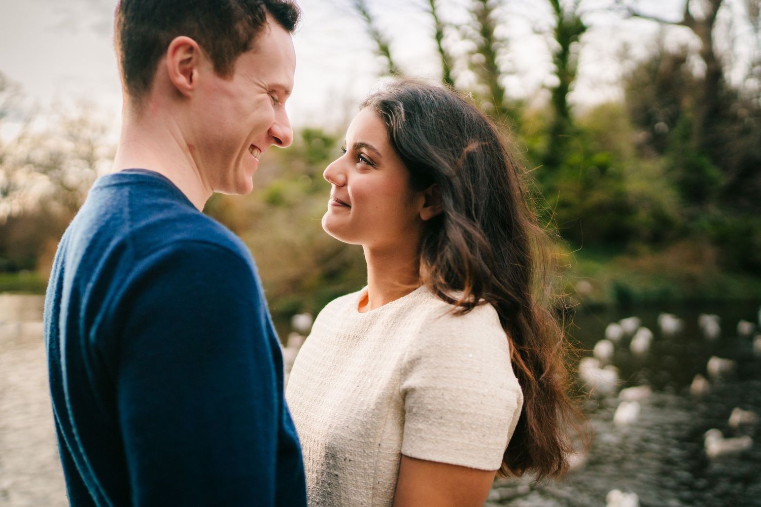 A couple in winter clothing share an intimate moment outdoors in a natural setting with golden light. Surprise proposal dublin photography