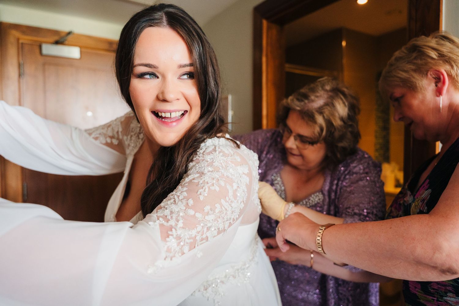Final preparations being made to a wedding dress with intricate lace details. Portmarnock Hotel Wedding PHOTOGRAPHER Dublin