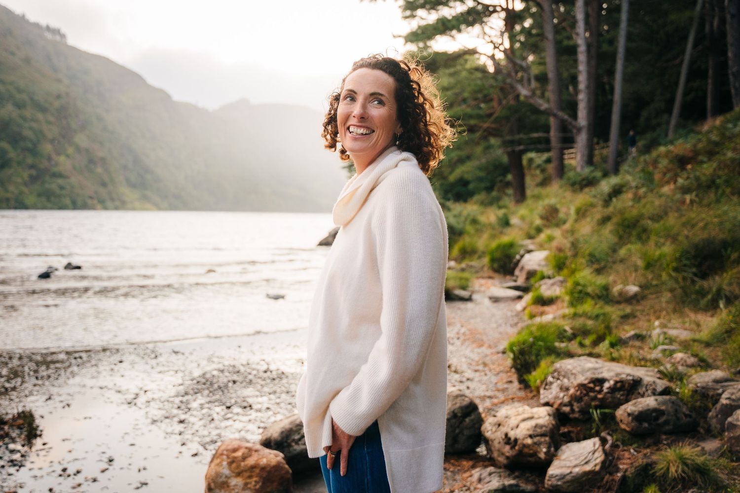 Family photographer Ireland Dublin Friends enjoying a scenic lakeside moment with mountains and trees in the background.