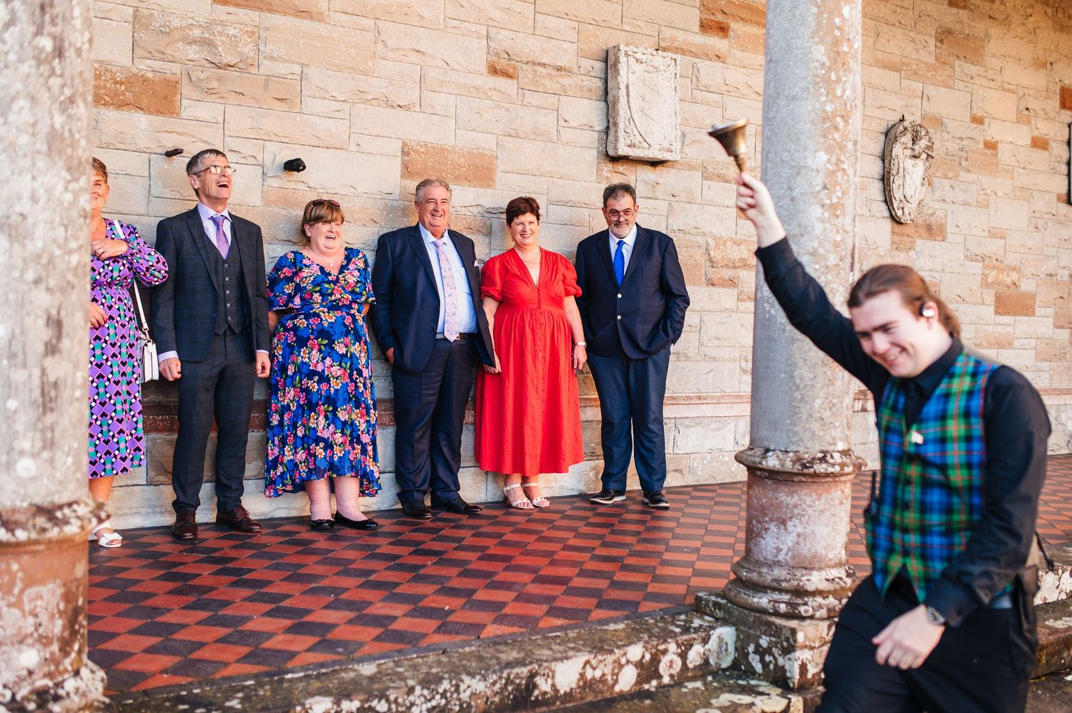 Castle Leslie Wedding Photographer Dublin Wedding party and guests line up against stone wall for formal group photo.