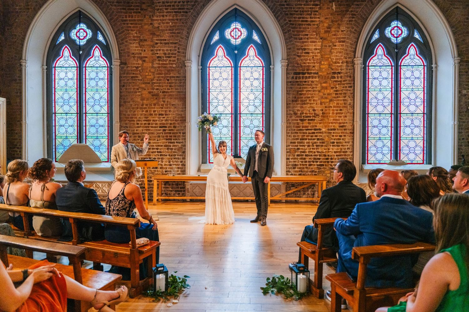Wedding ceremony in historic chapel with stained glass windows and exposed brick walls. PHOTOGRAPHER Dublin Ireland Wedding