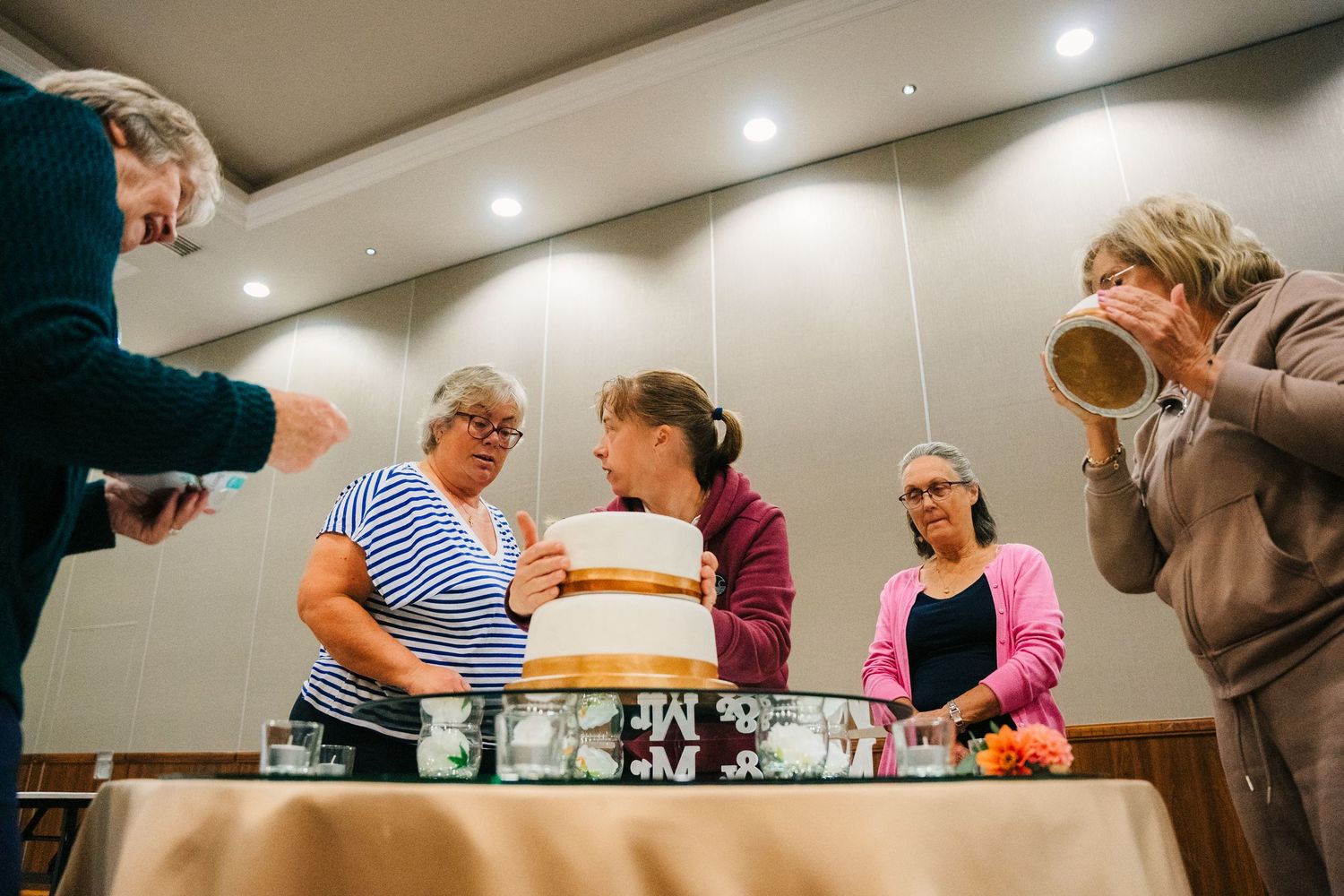 People gathered around a tiered cake during a baking class in a modern kitchen setting. Wedding Photography Trim Castle Ireland