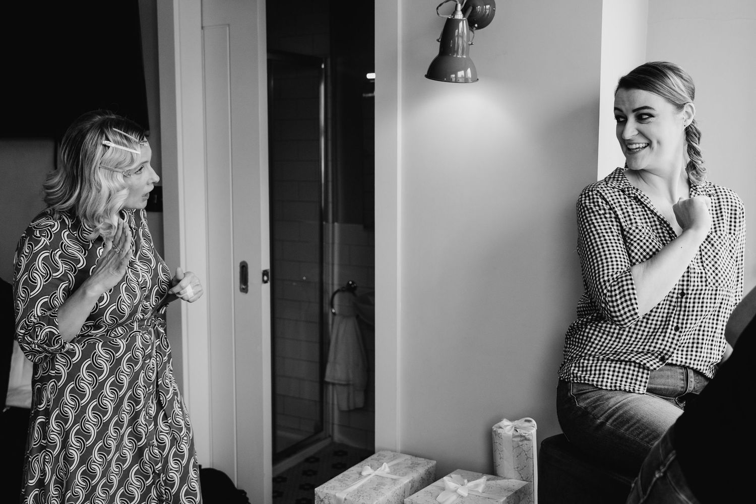 A candid black and white photograph of two people laughing while positioned on opposite sides of a hallway. House Dublin Wedding Photographe