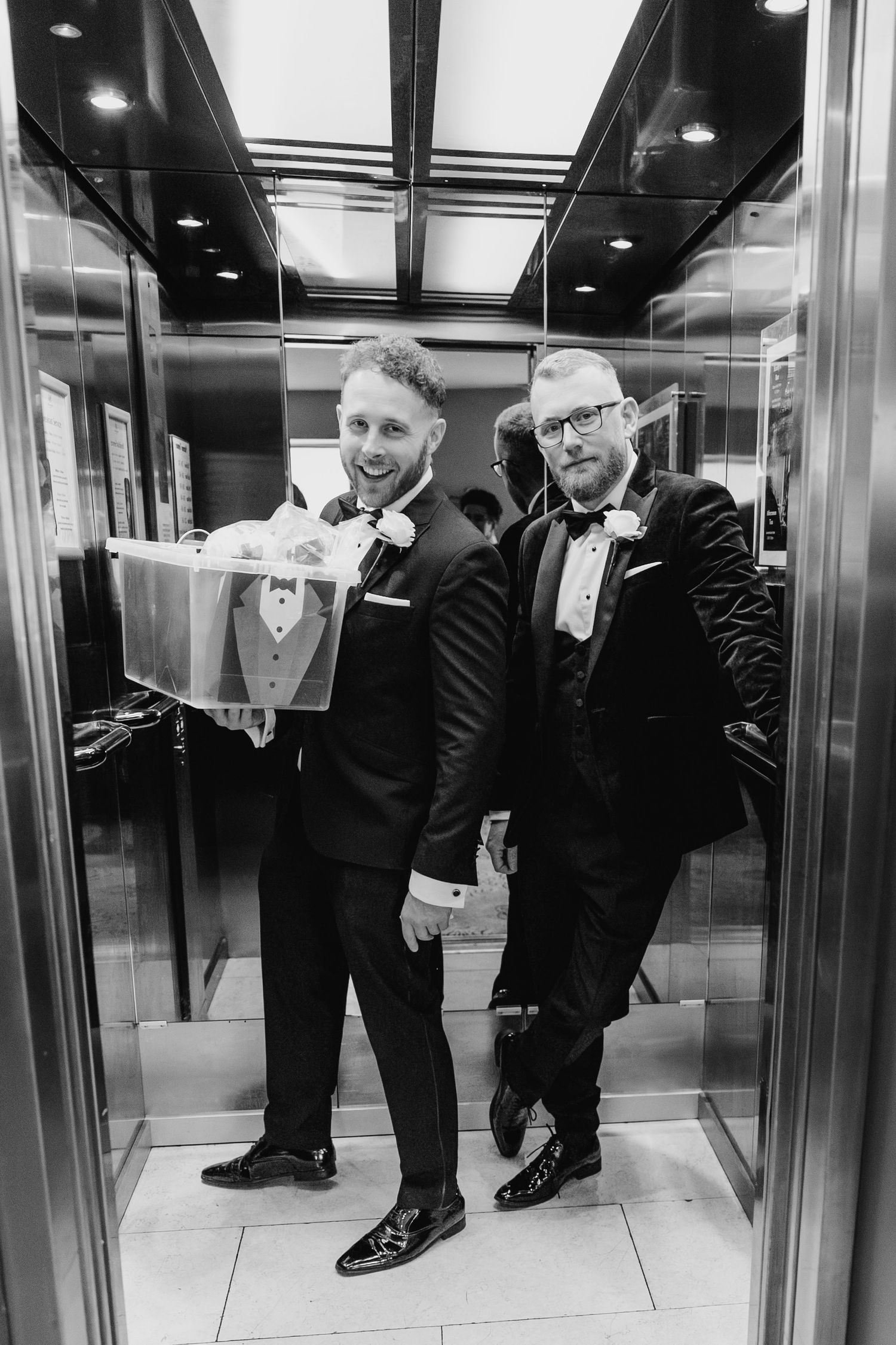 Royal Marine Hotel Dun Laoghaire Wedding Photographer Dublin PhoTwo grooms in tuxedos pose together inside an elevator on their wedding day.