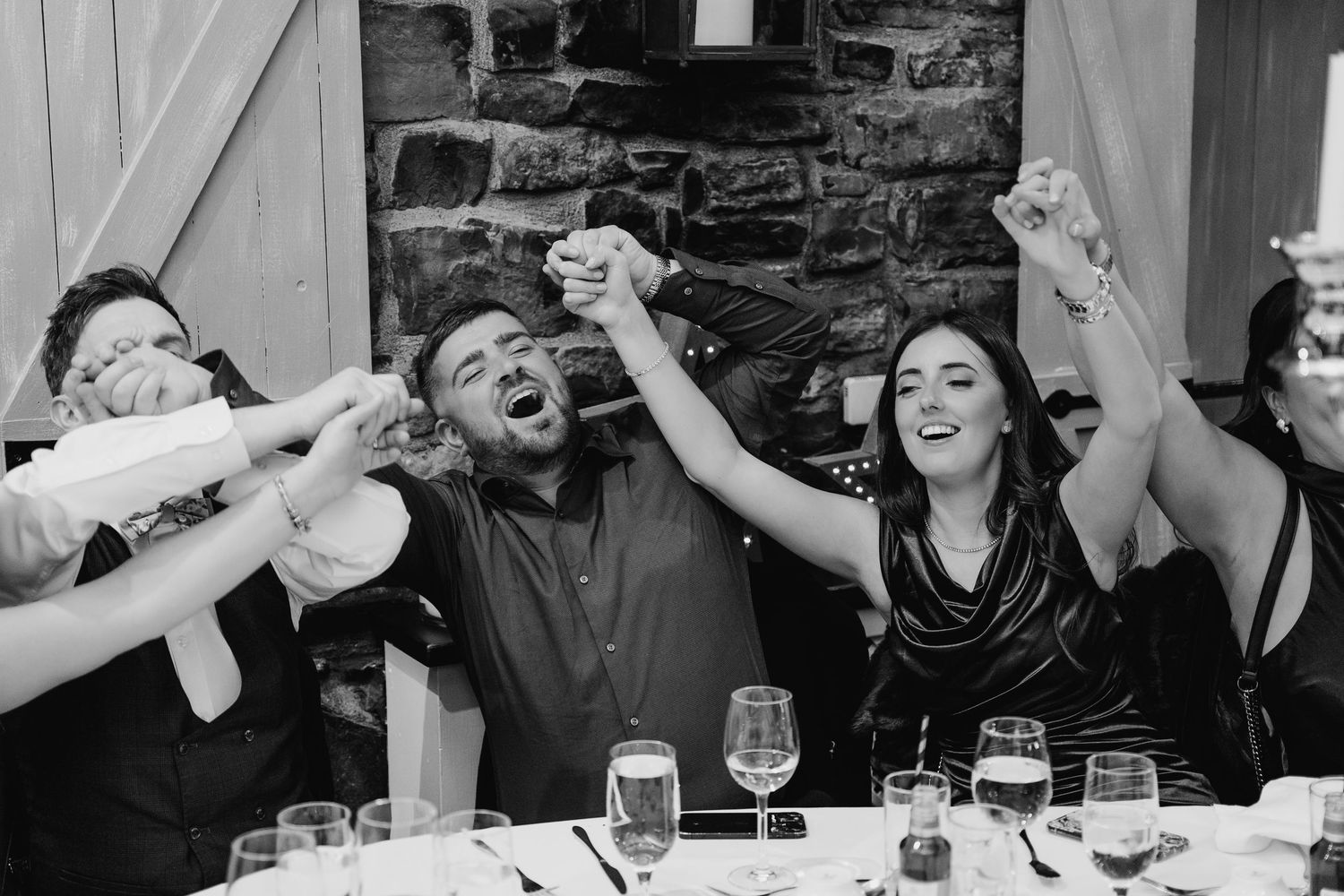 A sequence of black and white photos showing people laughing and enjoying themselves at a dinner party. Wedding photographer Dublin IReland
