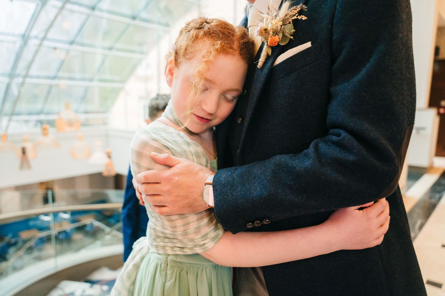 Young child in formal attire being held up while dancing in a sunlit venue. Marco Pierre Dublin Wedding Photographer