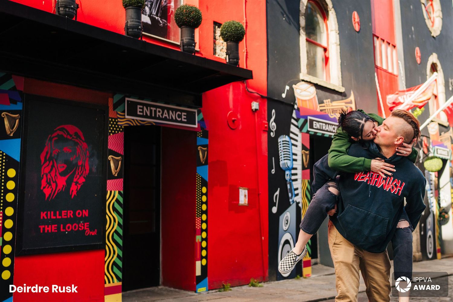 Couple outside red-painted entertainment venue with neon lights and urban artwork. Photographer dublin ireland couples
