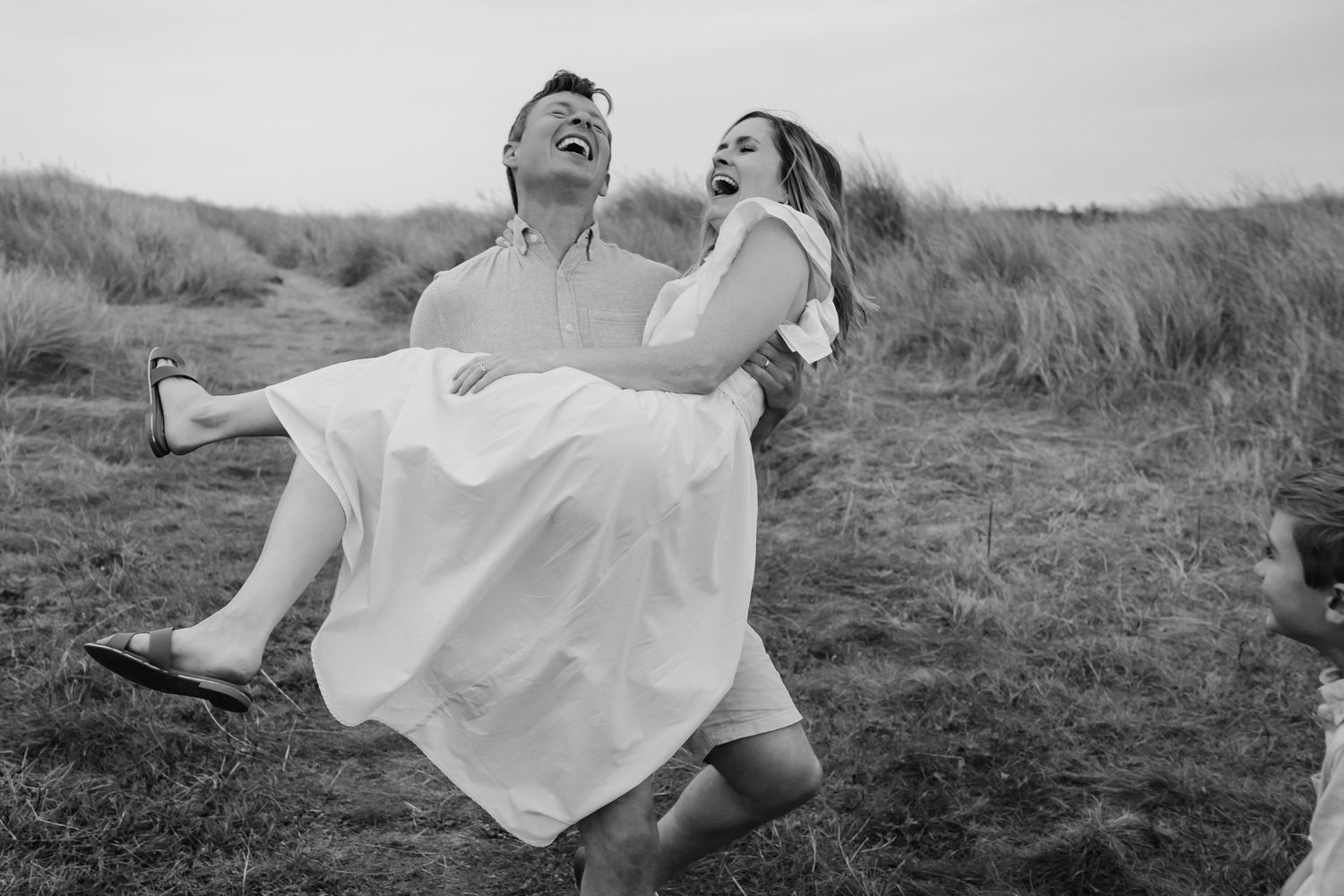 Black and white photo of a playful moment with a couple in wedding attire celebrating outdoors.  Family photographer Dublin Ireland