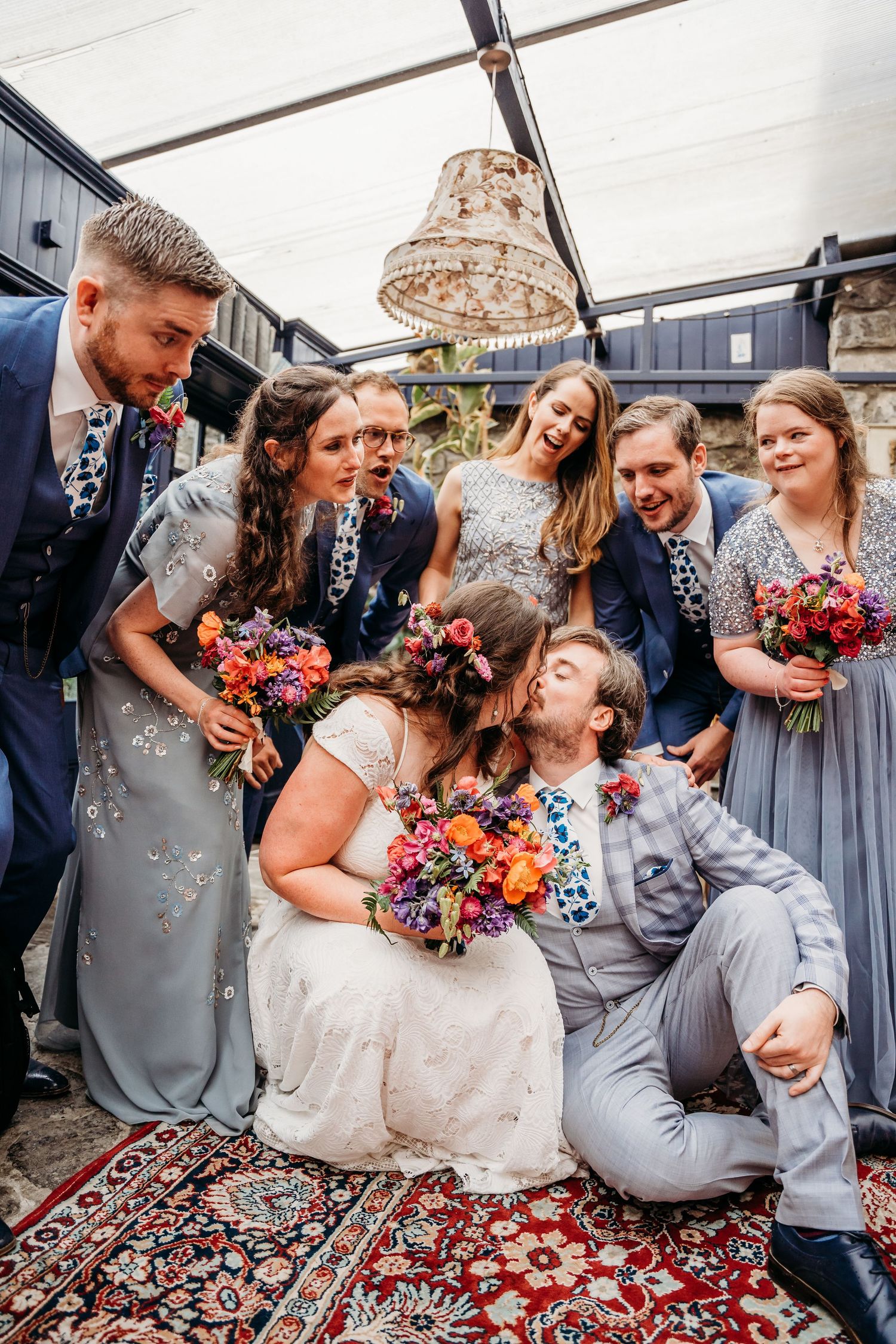 Wedding party sitting on ornate rug sharing candid laughs during photo session. Wedding photographer Dublin