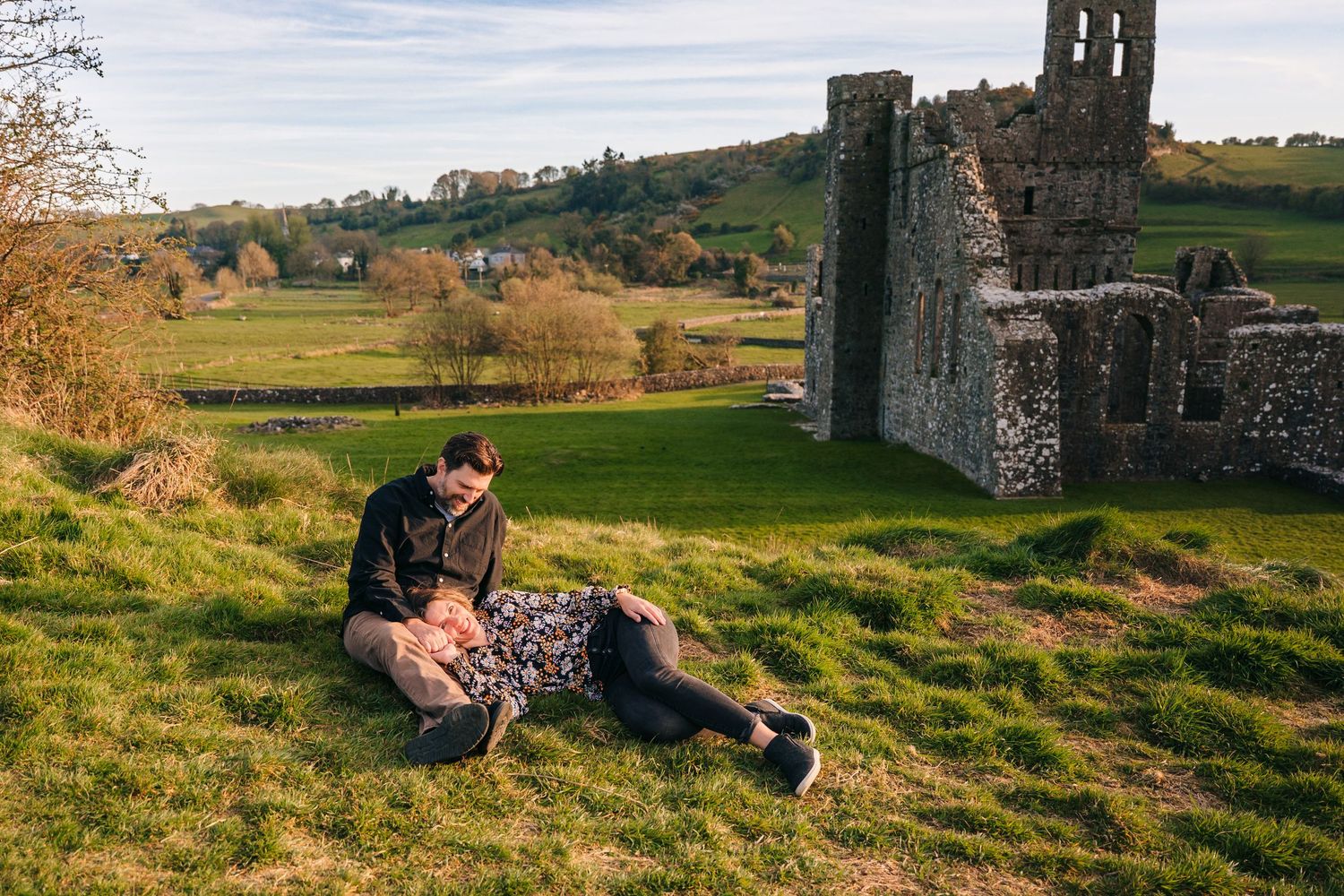 Intimate couples photography session on rolling green hills with medieval castle ruins in background. Photographer Ireland dublin