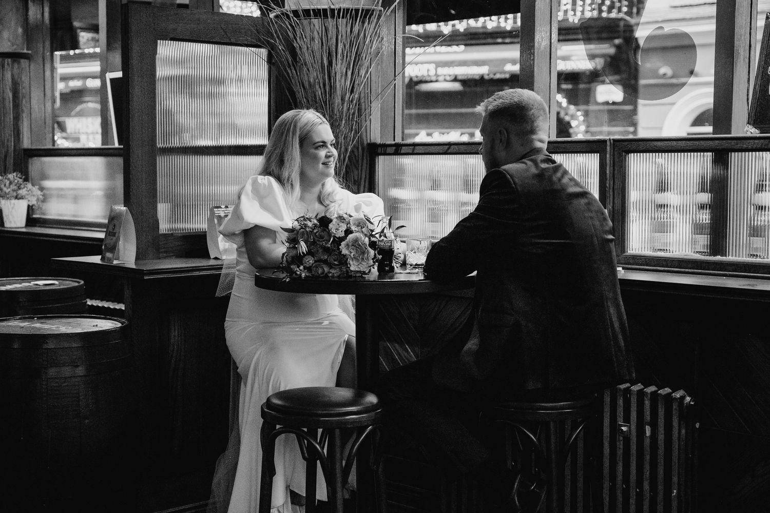 Black and white image of a couple sharing an intimate moment at a restaurant bar counter. City Hall Dublin Photographer