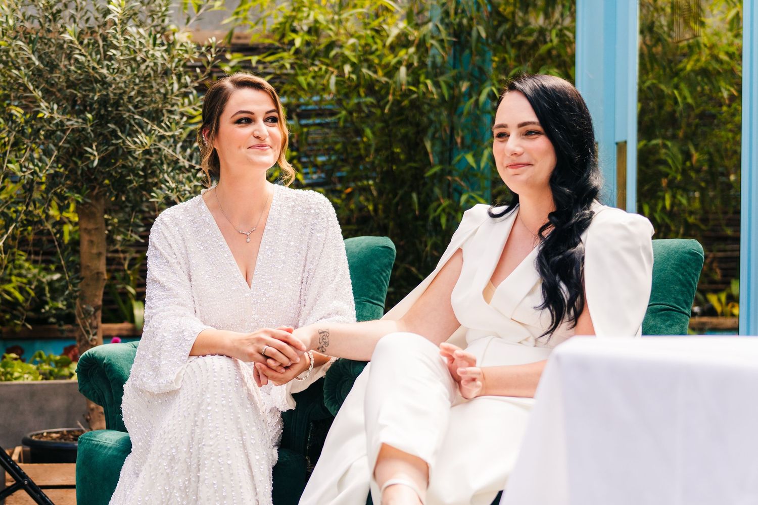 Two people in white attire seated on emerald green chairs at an outdoor event. House Dublin Wedding Photographer