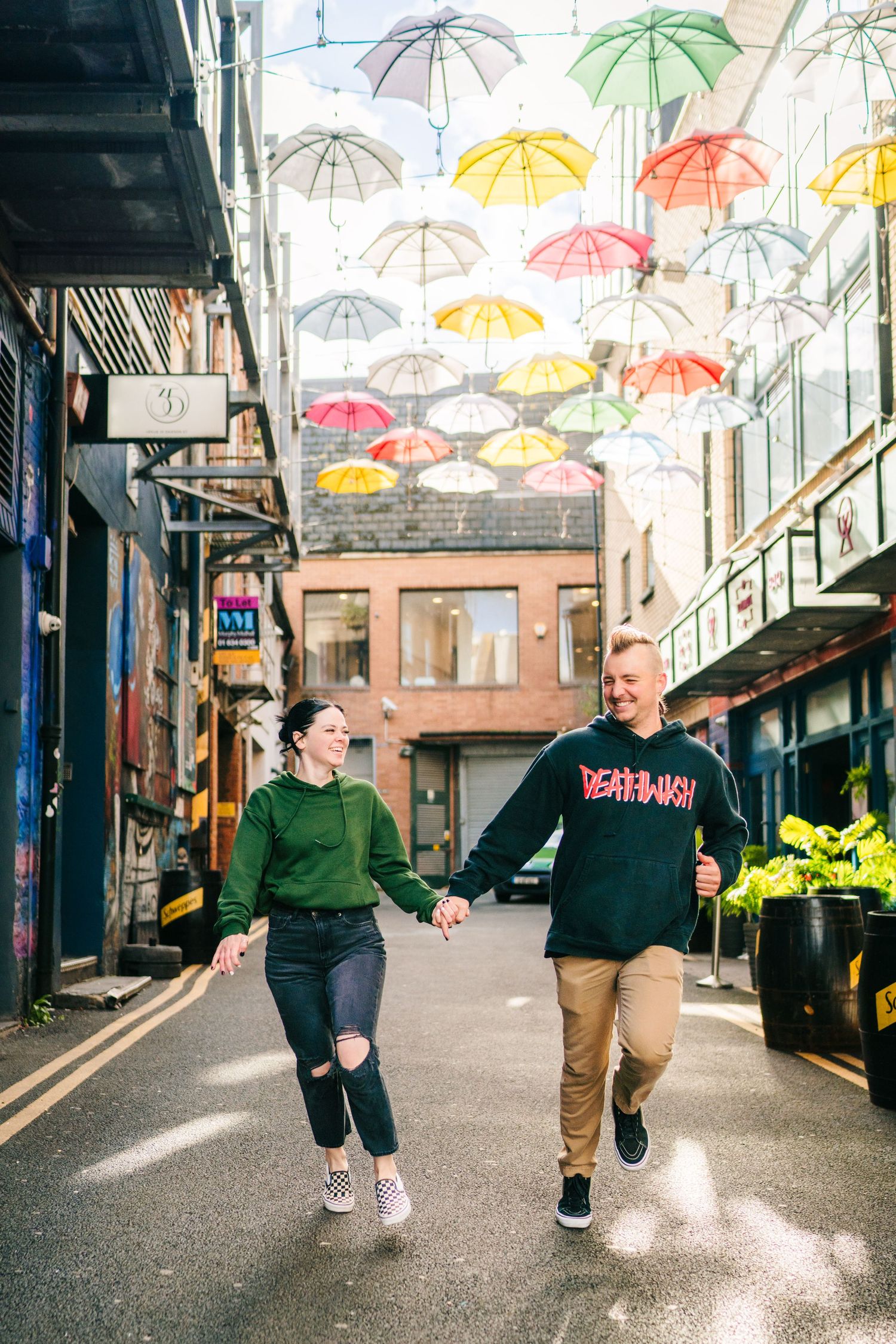 Colorful umbrellas hang above an urban alleyway creating a whimsical canopy. PHOTOGRAPHER Dublin Ireland
