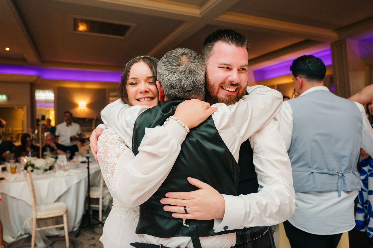 Wedding guests dance and celebrate at an indoor reception with purple lighting. Portmarnock Hotel Wedding PHOTOGRAPHER Dublin