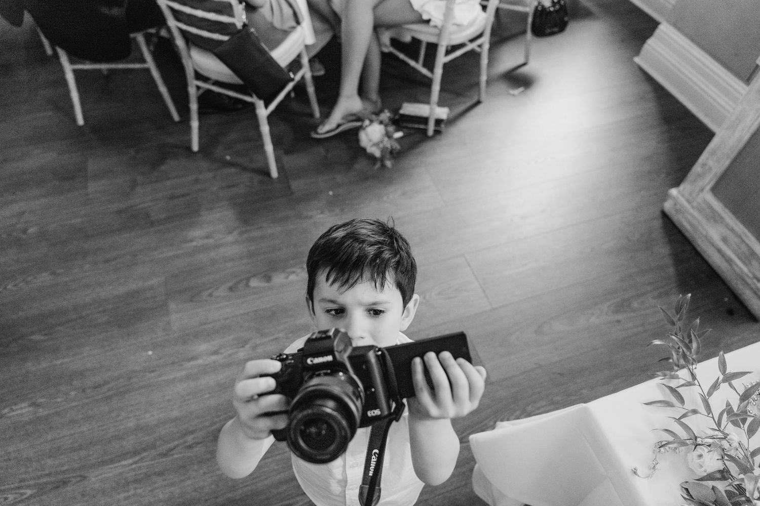 Child at wedding plays with camera in candid black and white photo series. PHOTOGRAPHER Dublin Ireland Wedding
