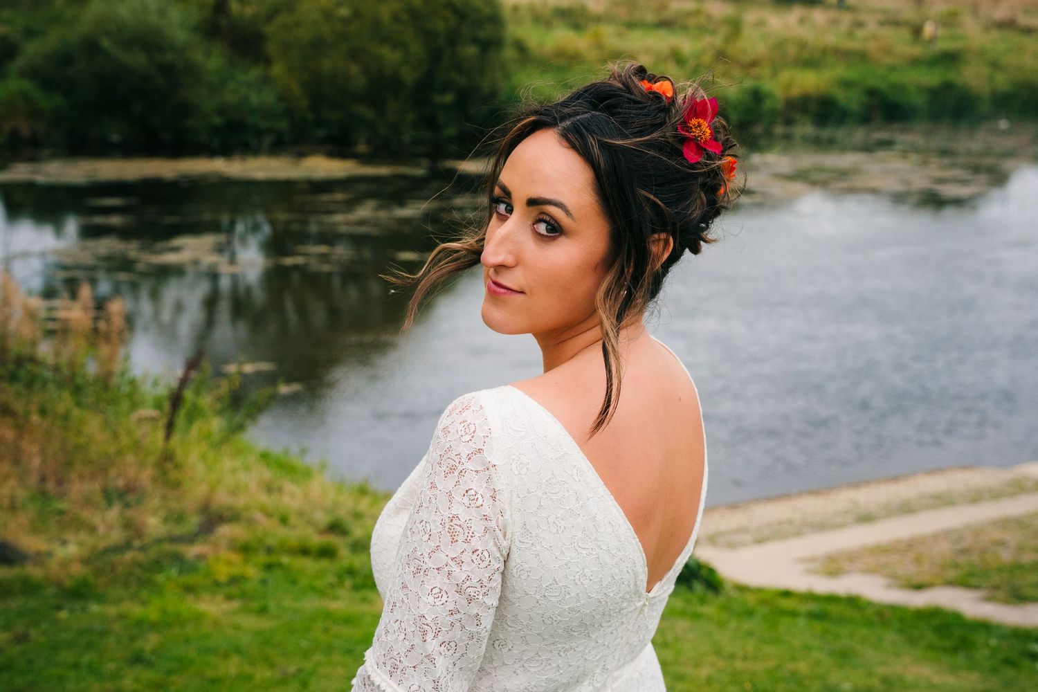 Elegant lace wedding dress with open back detail captured by lakeside setting.Wedding Photography Trim Castle Ireland